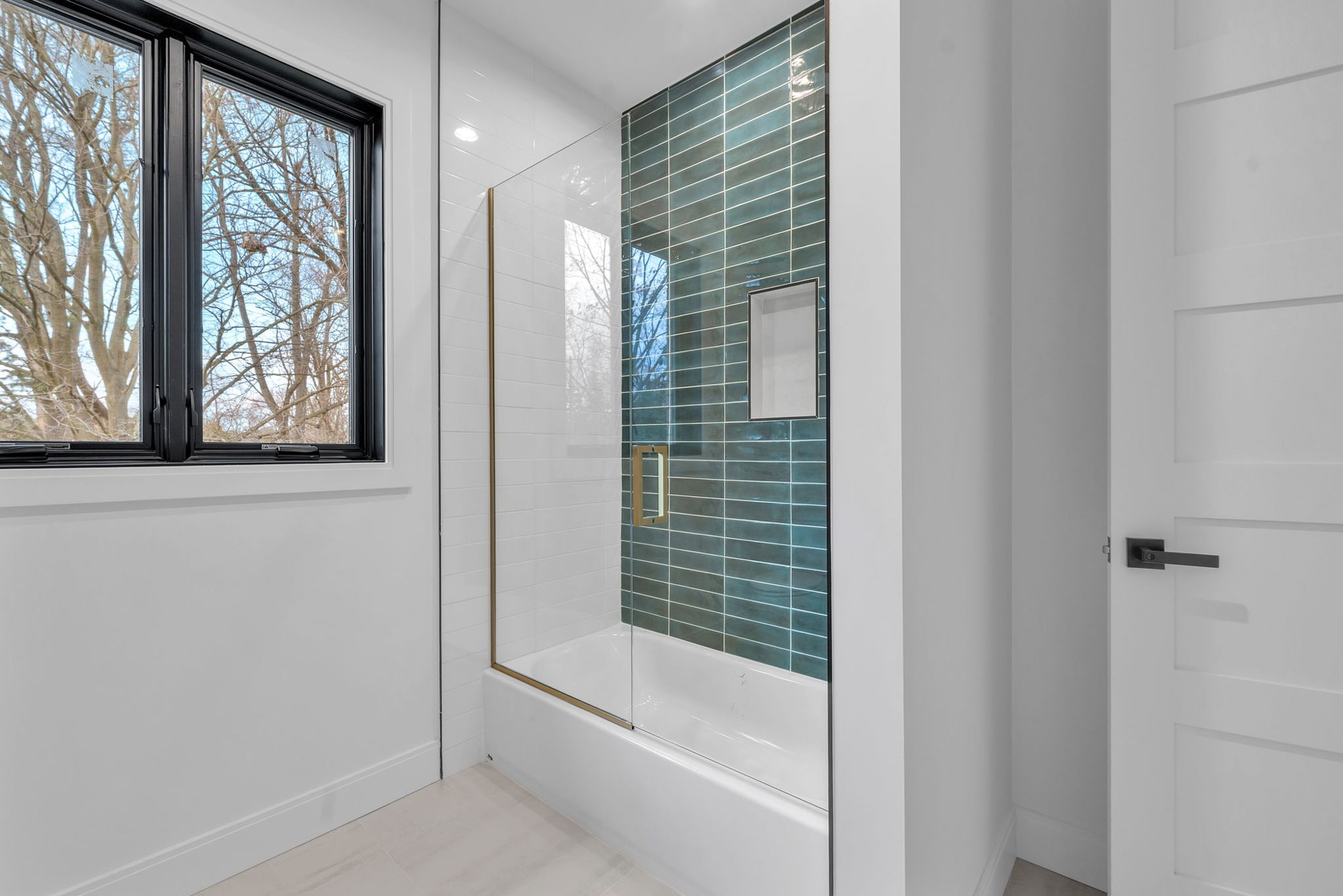 Tub and shower with green glazed tile and brass glass door