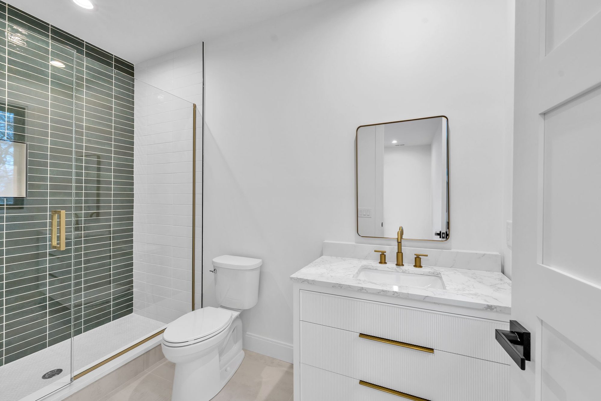 White fluted vanity beside a green tiled shower