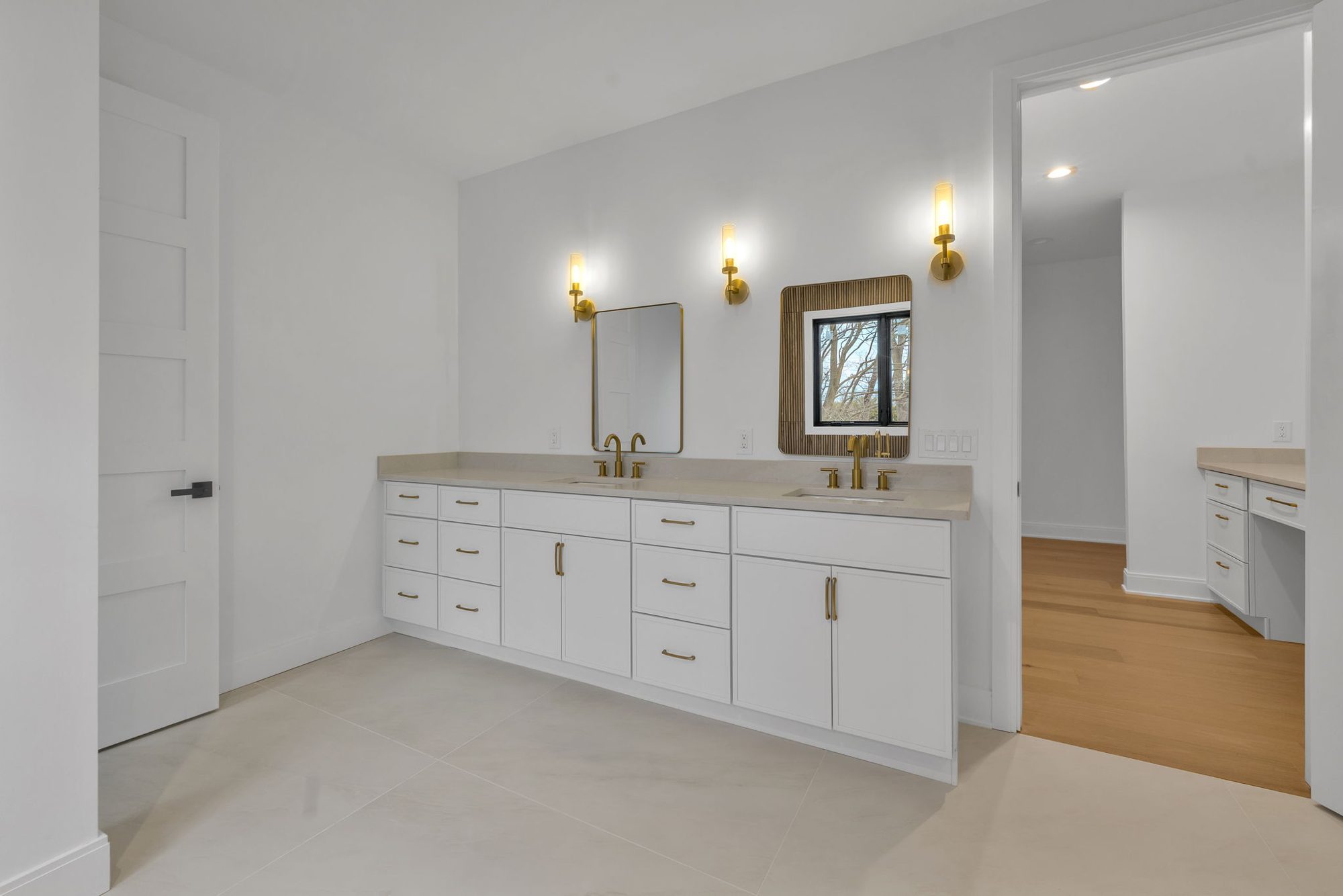 White double vanity with brass faucets and sconces
