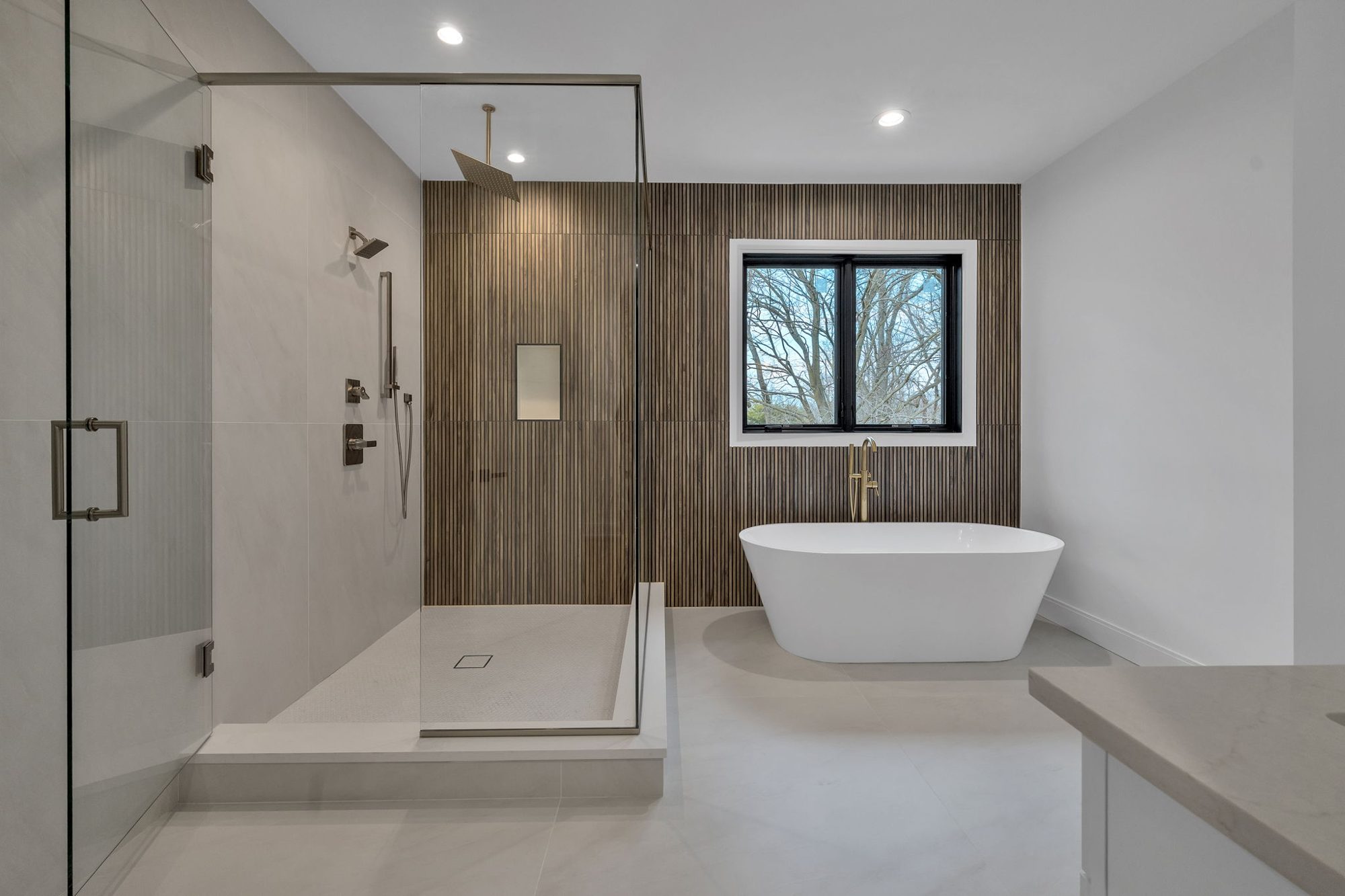 Primary bath with wood slat wall, freestanding tub and glass shower
