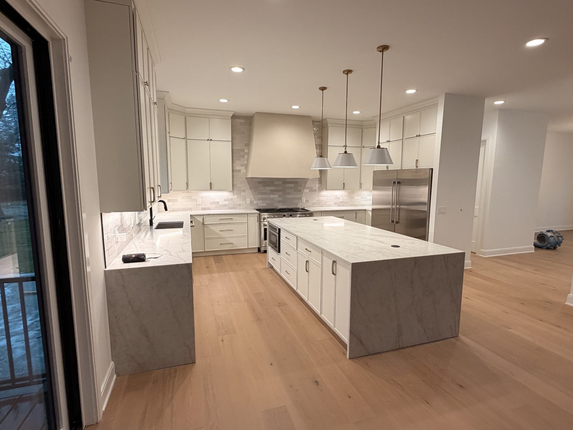 Cream kitchen with fluted marble island, zellige backsplash and plaster range hood