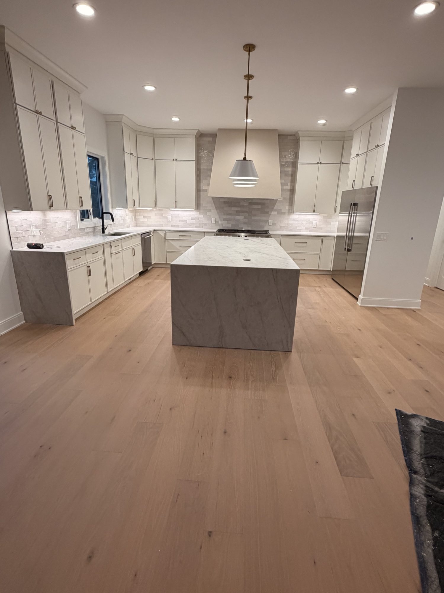 Wide view of cream kitchen with marble island and white oak floors