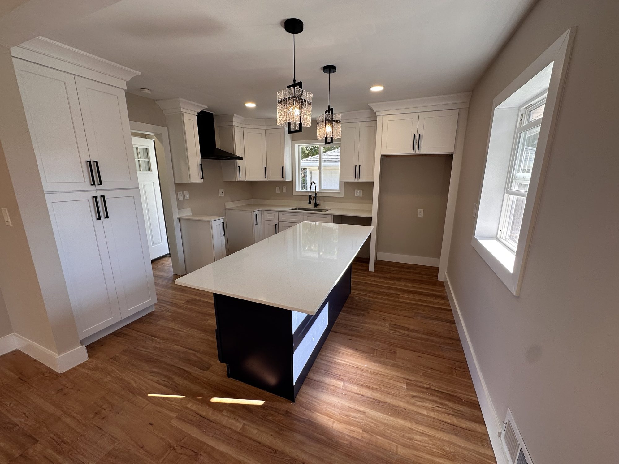 White shaker kitchen with black island and crystal pendants