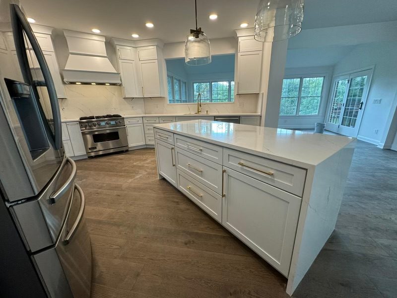 White shaker kitchen with brass pulls and a quartz waterfall island