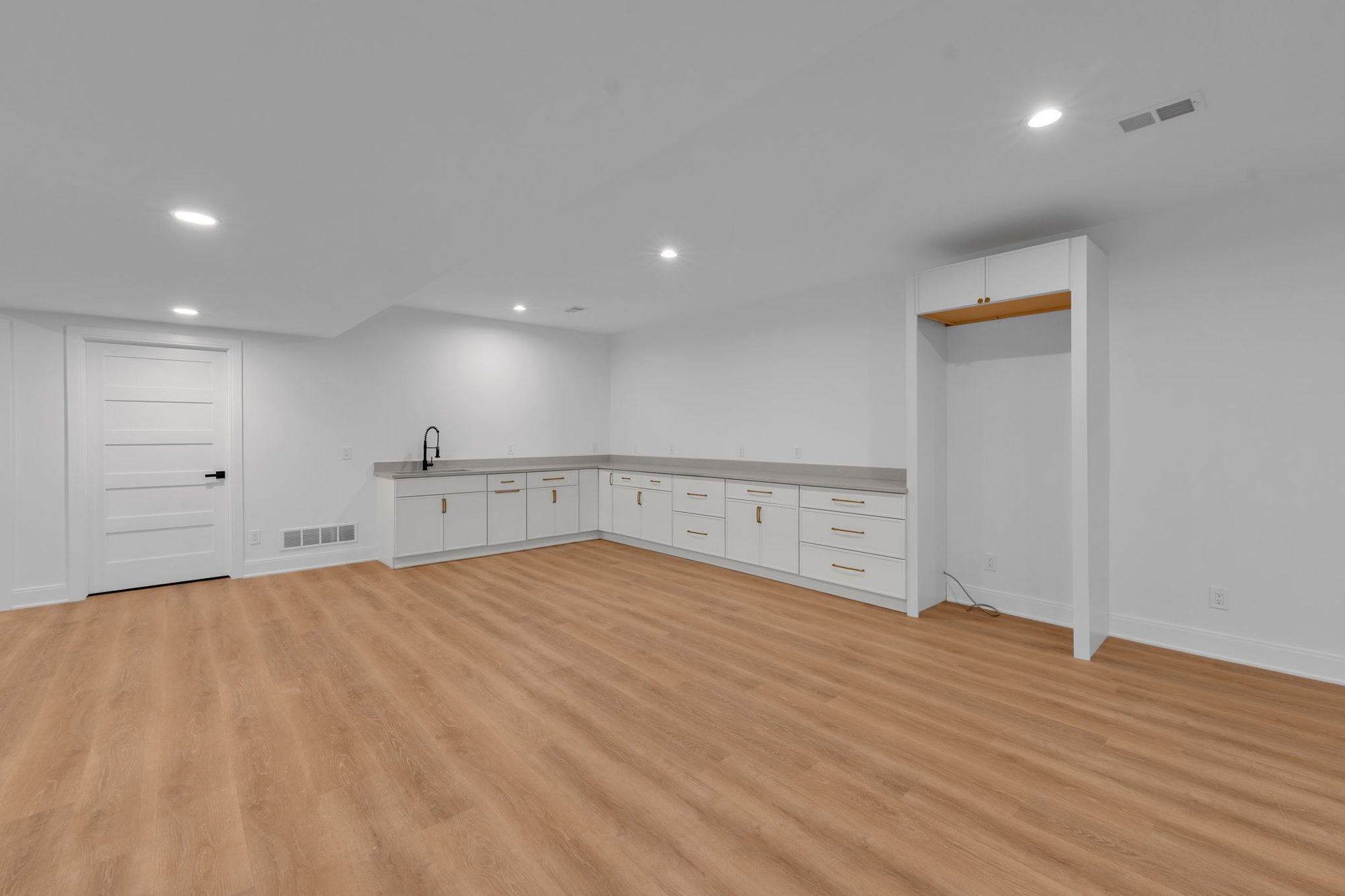 Basement kitchenette with white cabinets and quartz counter