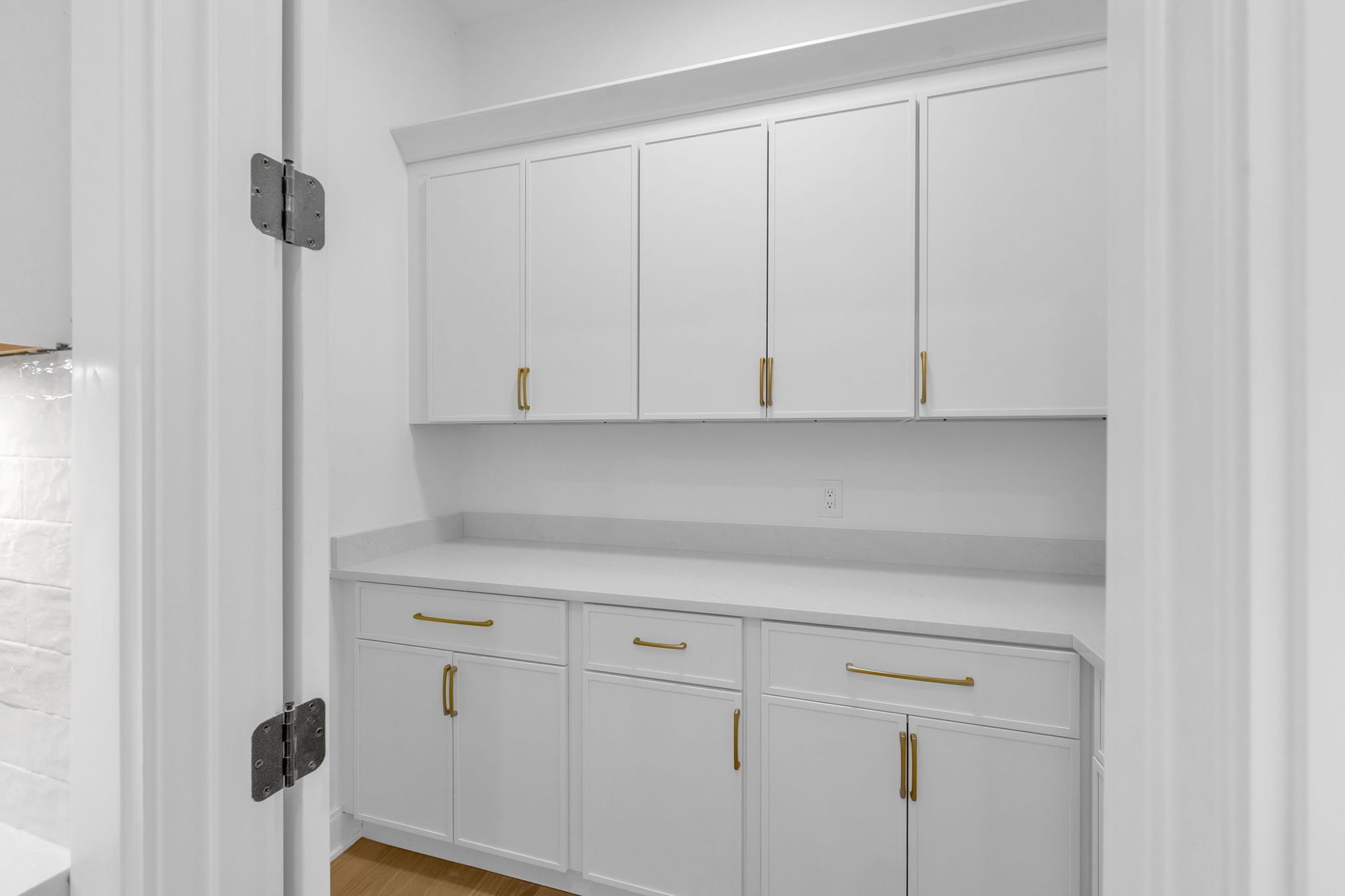Butler's pantry with white cabinets and brass pulls