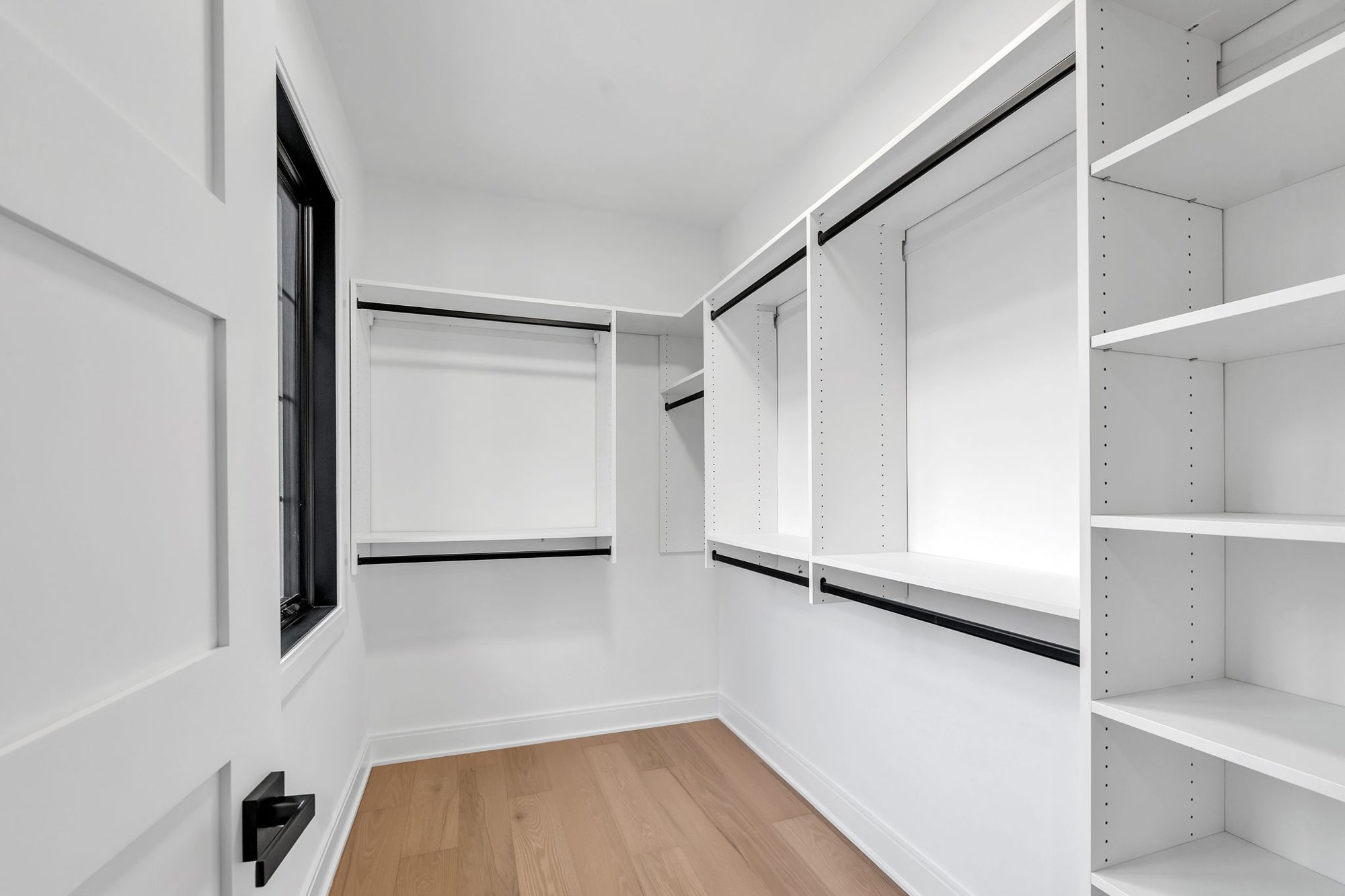 Walk-in closet with white shelving and black rods