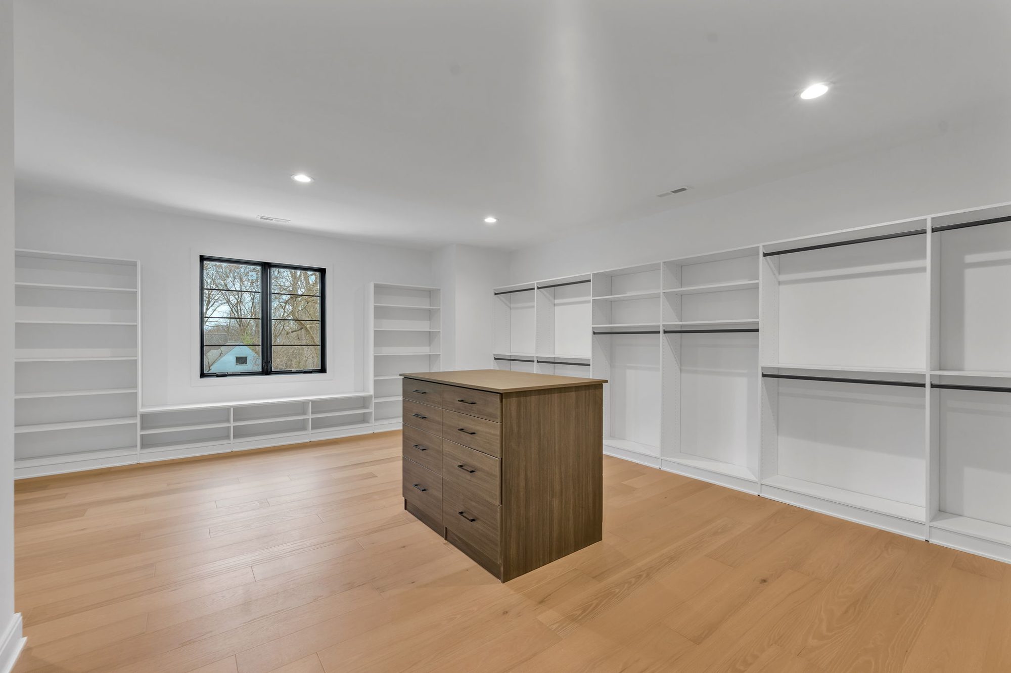 Walk-in closet with white shelving and walnut island